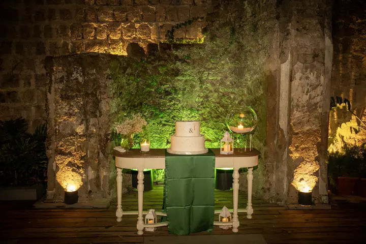 Tavolino con la torta tra luci e muro verde